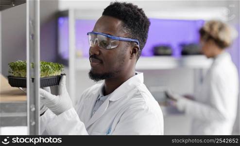 male researcher laboratory with safety glasses plant