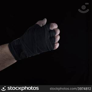 male right hand is wrapped in a black sports textile bandage on a black background
