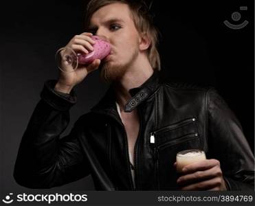 Male rocker wearing black leather jacket and he drinks smoothie, dark background and studio shot