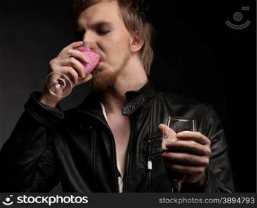 Male rocker wearing black leather jacket and he drinks smoothie, dark background and studio shot