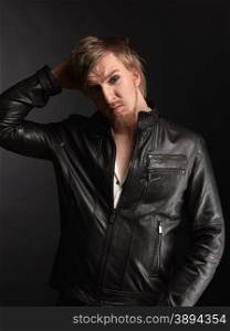 Male rocker wearing black leather jacket, dark background and studio shot