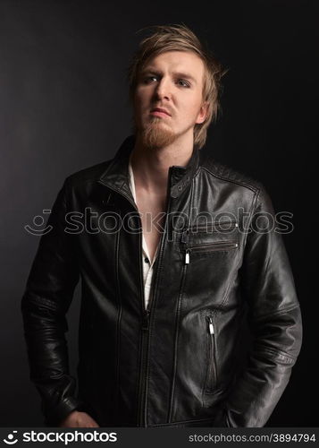 Male rocker wearing black leather jacket, dark background and studio shot