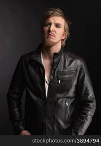 Male rocker wearing black leather jacket, dark background and studio shot