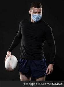 male rugby player with medical mask holding ball