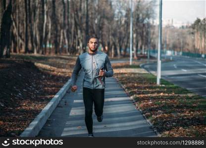 Male runner in sportswear on training outdoor. Jogger on morning workout. Athletic man running marathon