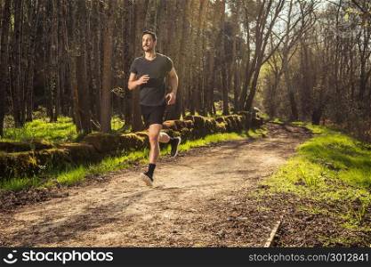 Male runner on nature road in misty forest full of pleasure warm light.