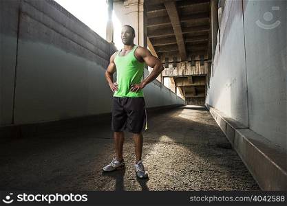 Male runner taking a break under city bridge
