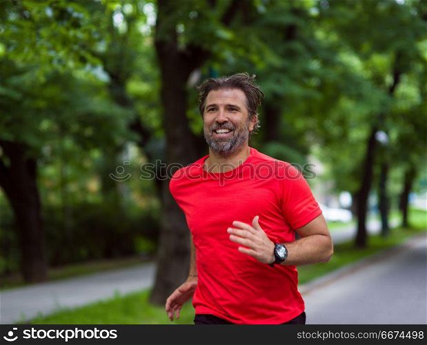 male runner training for marathon. fit muscular male runner training for marathon running on beautiful road in nature.