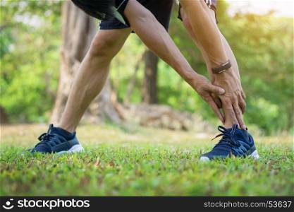 Male runner training in cold winter doing warm-up leg stretching exercise
