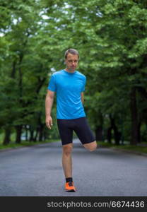 male runner warming up and stretching before morning training. healthy male runner warming up and stretching in city park before morning training