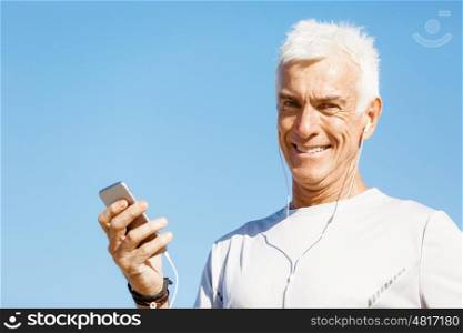 Male runner with his mobile smart phone standing outdoors. Young male runner with his mobile smart phone standing outdoors