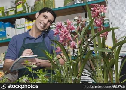 Male sales clerk taking order in a flower shop and smiling