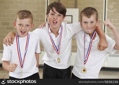 Male School Sports Team In Gym With Medals