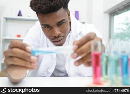 male scientist closely examining test tube