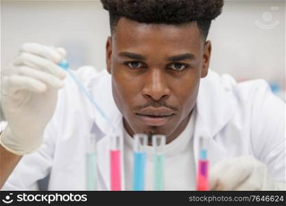 male scientist in protective gloves loads blue liquid sample