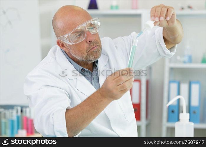 male scientist in the medical laboratory filling test tubes
