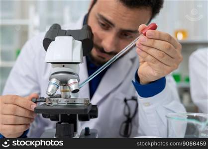 Male scientist in white lab coat dropping chemical liquid on slide and using microscope in laboratory research and development. Science and Technology concept