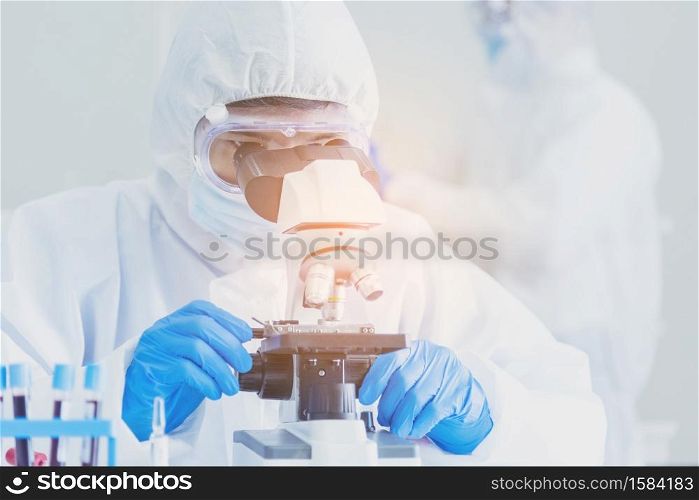 Male Scientist look into Microscope research in science laboratory. Asian scientist looking equipment laboratory chemistry labs. Covid-19 coronavirus biochemistry research experiment vaccine concept