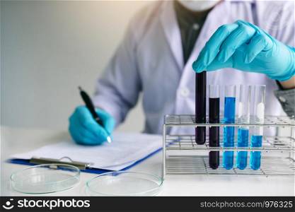 Male scientist worker in white coat working with test tubes in laboratory.