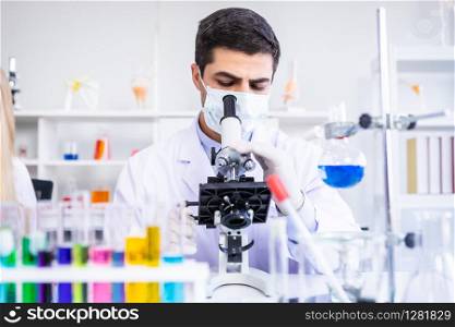 Male scientist working looking at Microscope with sample test tube in a chemistry lab scientist researcher are doing investigations in Laboratory analysis background