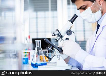 Male scientist working looking at Microscope with sample test tube in a chemistry lab scientist researcher are doing investigations in Laboratory analysis background
