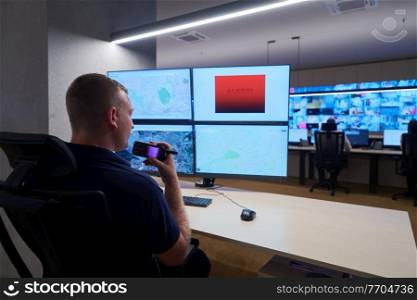 Male security operator working in a data system control room offices Technical Operator Working at  workstation with multiple displays, security guard working on multiple monitors  Male computer operator monitoring from a security center Alarm signal on the screen