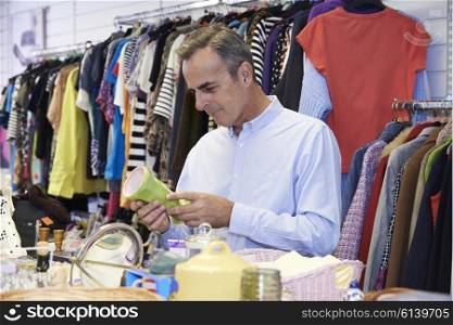 Male Shopper In Thrift Store Looking At Ornaments