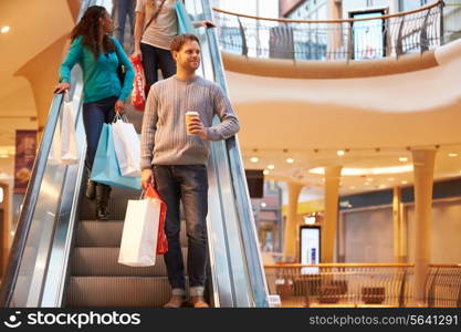 Male Shopper On Escalator In Shopping Mall