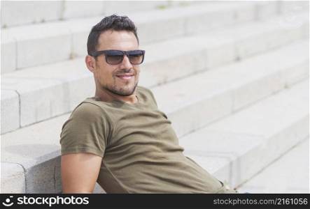 Male sitting alone on steps. Handsome boy with sunglasses