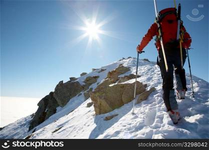 Male ski-climber climbing a snowy ridge; horizontal frame. Italian alps.