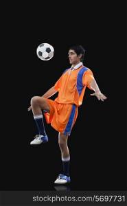Male soccer player doing kick ups isolated over black background