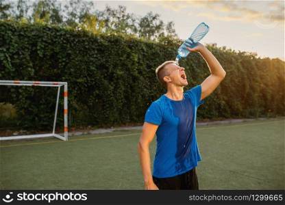 Male soccer player doused with water on his head on the field. Footballer on outdoor stadium, workout before game, football training