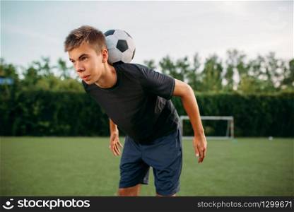 Male soccer player keeps balance with the ball on his neck on the field. Footballers on outdoor stadium, team workout before game