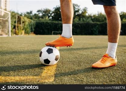 Male soccer player legs with ball standing on line on the field. Footballer on outdoor stadium, workout before football match