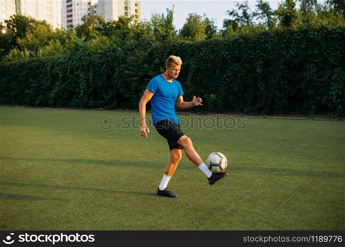 Male soccer player with ball standing on line on the field. Footballer on outdoor stadium, workout before football match. Male soccer player with ball standing on line