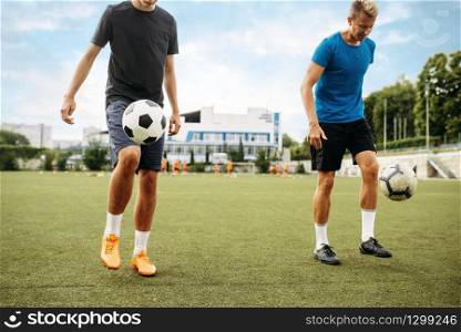 Male soccer players stuffs the ball with their feet on the field. Footballers on outdoor stadium, team workout before game