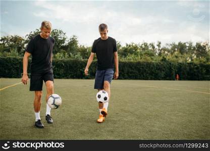 Male soccer players training with balls on the field. Footballers on outdoor stadium, team workout before game. Soccer players training with balls on the field