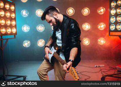 Male solo musican with electro guitar on the stage with the decorations of lights. Music entertainment.. Male solo musican with electro guitar
