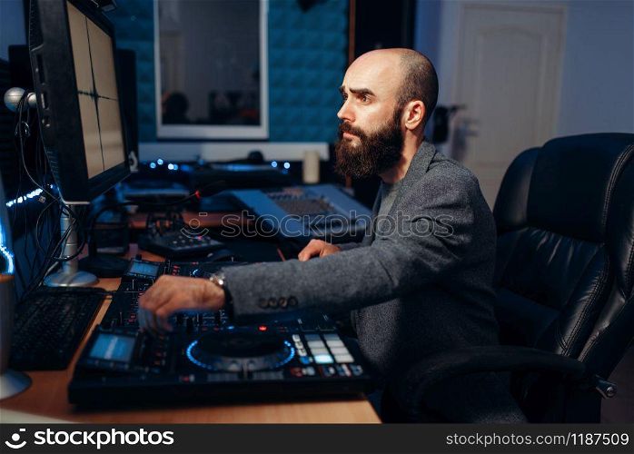 Male sound editor at remote control panel in the recording studio. Musician at the mixer, professional audio mixing. Male sound editor in the recording studio