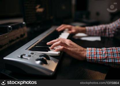 Male sound producer hands on musical keyboard, closeup. Digital audio recording technology. Media engineering