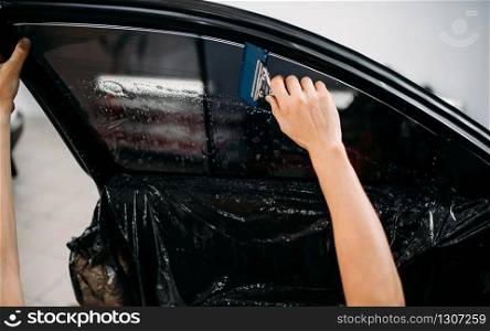 Male specialist work with car, tinting film installation process, tinted auto glass installing procedure. Specialist work with car, tinting film installing