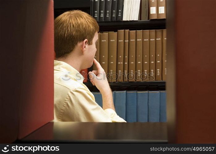 Male student choosing a book in the library