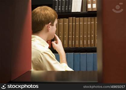 Male student choosing a book in the library