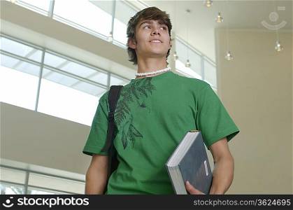 Male student holding book in university