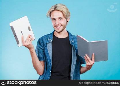 Male student holding ebook reader and book. Choice between modern educational technology and traditional way method. Young guy with digital tablet pc and textbook.. Man student holding tablet and book.
