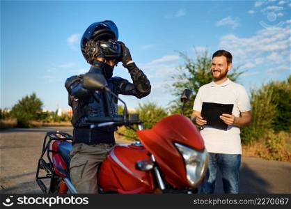 Male student in helmet and instructor, driving course on motordrome, motorcycle school. Training of motorcyclists beginners, biker practicing in motorschool. Student and instructor, driving course, motordrome