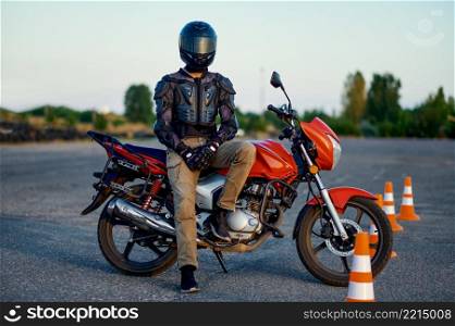 Male student poses on motorbike, riding on motordrome in motorcycle school. Training of motorcyclists beginners, biker practicing in motorschool. Male student poses on motorbike, motorcycle school