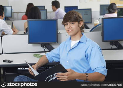 Male student sitting in computer classroom, portrait