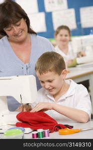 Male student using sewing machine with teacher