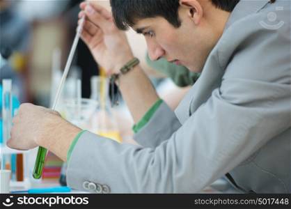 Male student with group of classmates on background working at the school or college or university laboratory during chemical lesson